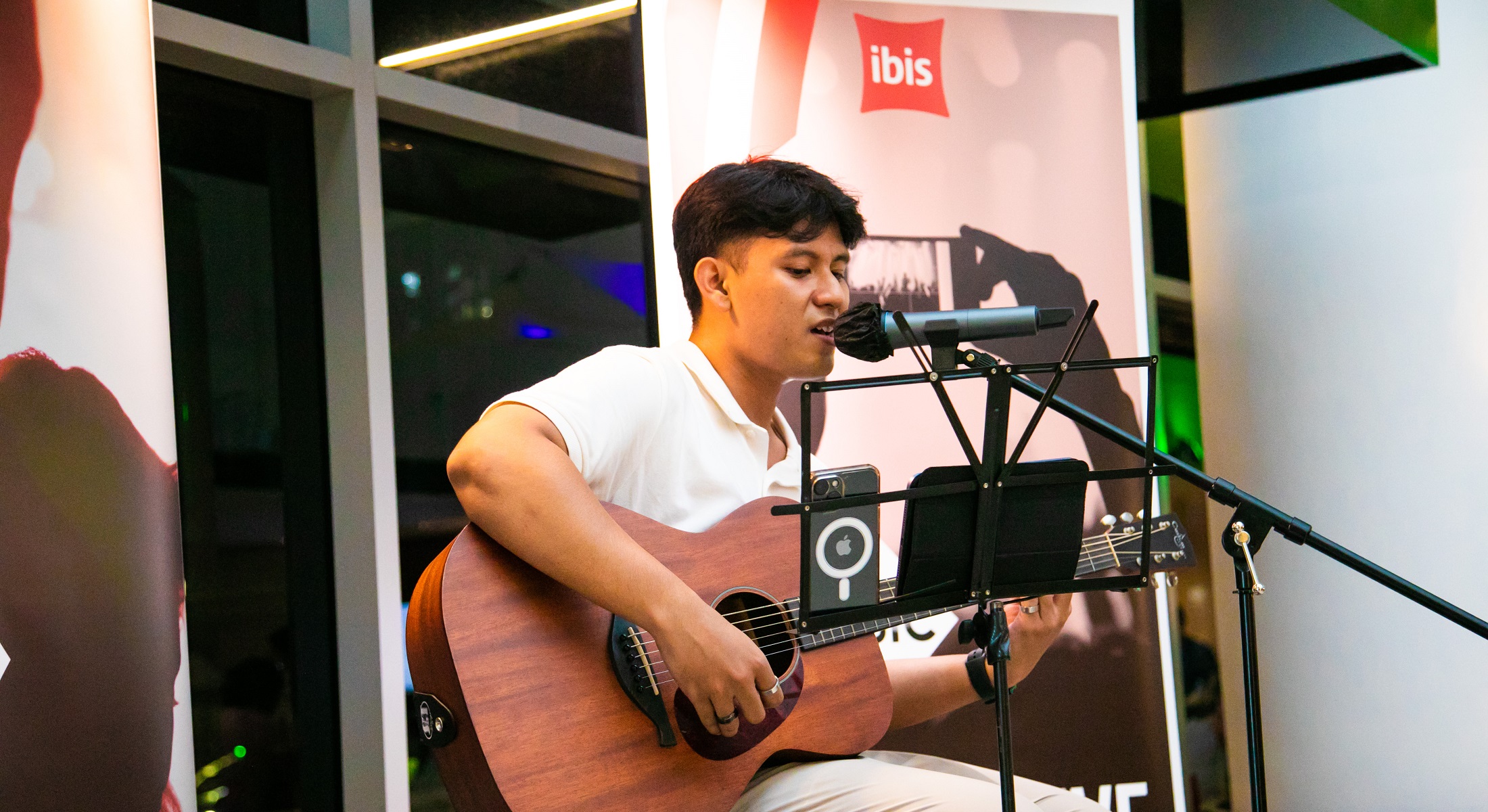 A local solo performer playing guitar and singing at an Ibis Music event.